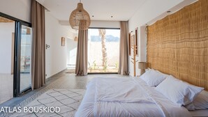 Hotellihuone, jossa on suuri sänky, riippuvalaisin ja näkymä ulos.