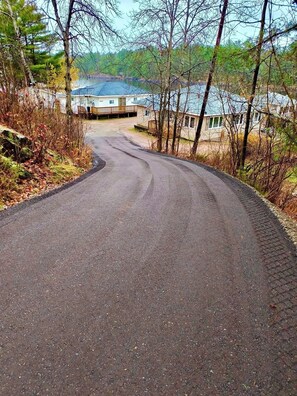 A winding road leading to a building with a dock, surrounded by trees and a body of water.