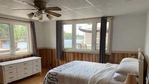 A bedroom with a bed, a nightstand, a dresser, and a ceiling fan.