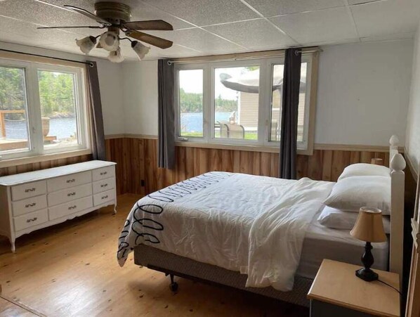 A bedroom with a bed, a nightstand, a dresser, and a ceiling fan.