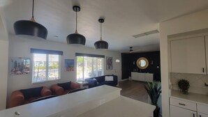 A modern kitchen with white cabinets, a central island, and pendant lighting. - Old Town Scottsdale modern decor big pool hot tub TV on patio Comfort Convenient (Scottsdale)
