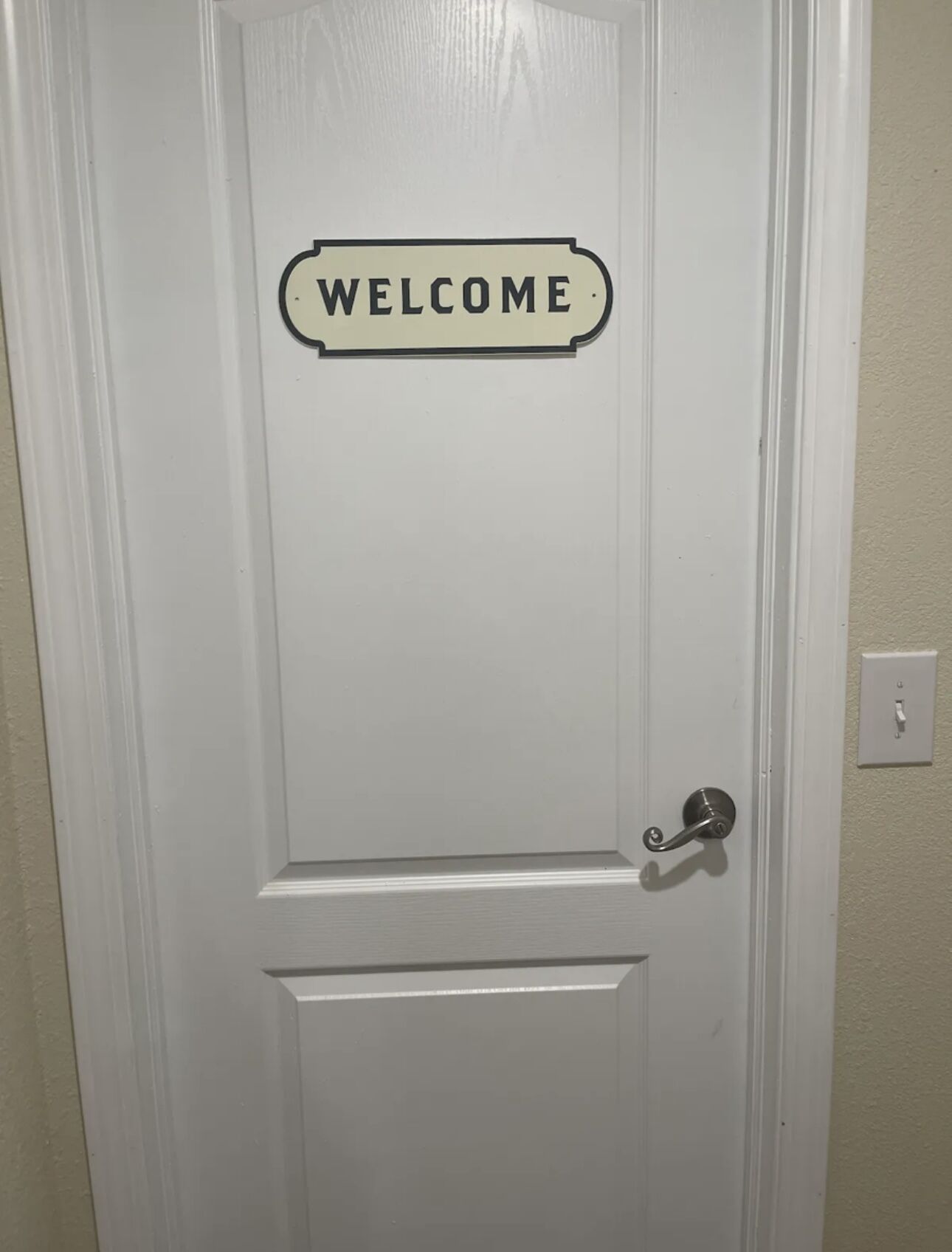 A white door with a "WELCOME" sign above it.