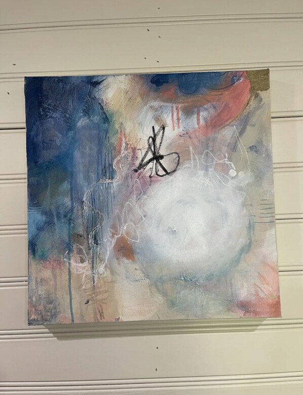 Una pintura con elementos abstractos y una figura negra central, colgada en una pared.