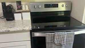 Una cocina con estufa de acero inoxidable, microondas y cafetera en la encimera.