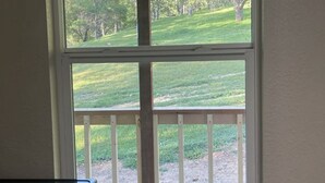 Una habitación con un ventanal grande que da a un área verde con árboles.