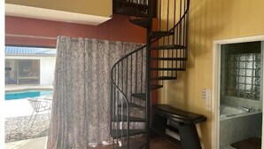 A room with a spiral staircase, a pool, and a bathroom with a bathtub. - Spacious Pool House....completely Private!! (Lakeland)