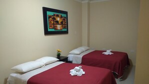 A hotel room with two beds, each with red bedding and white pillows. There is a framed picture on the wall above the beds. - Hotel Vanderkris Chone (Chone)