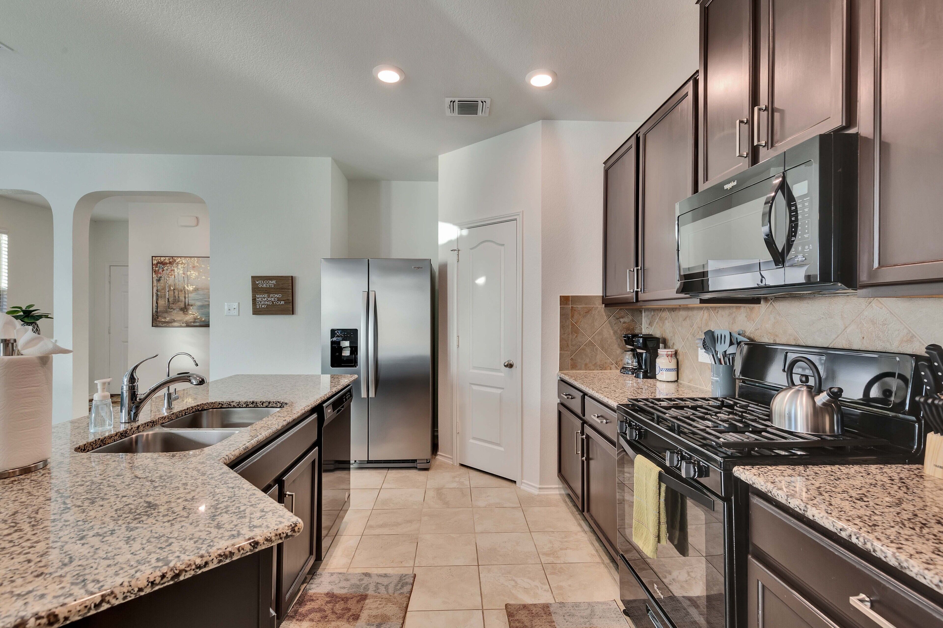 A modern kitchen with granite countertops, stainless steel appliances, and dark wooden cabinets.
