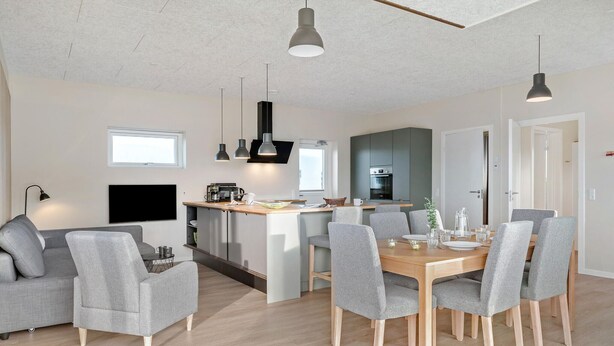 Una cocina moderna con una isla central, sillas tapizadas en gris y una mesa de comedor para seis personas.