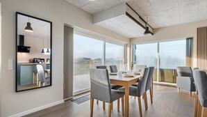 Un comedor moderno con una mesa grande, sillas tapizadas en gris y grandes ventanales con vistas al exterior.