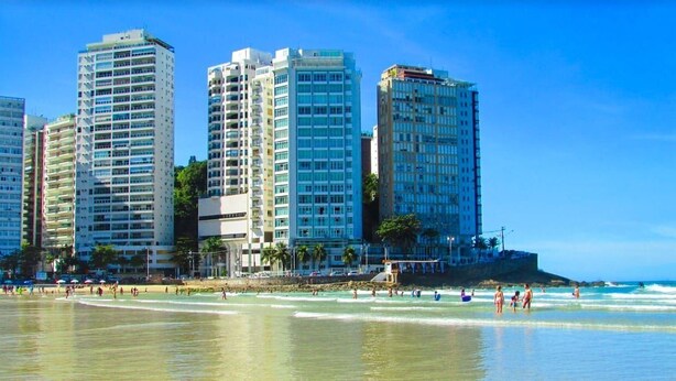 Un hotel frente a la playa con varios edificios altos, una playa de arena y olas del océano.