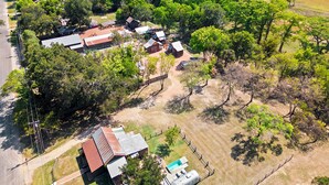 An aerial view of a rural property with multiple buildings, a fenced area, and a swimming pool. - Luxury 3 Bedroom House with Airstream, Cabin, Private Fireplace, and Plunge Pool (Comfort)