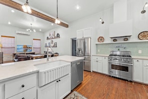A modern kitchen with white cabinetry, stainless steel appliances, and a wooden floor.