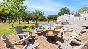 An outdoor seating area with Adirondack chairs, a fire pit, and a pool. - Luxury 3 Bedroom House with Airstream, Cabin, Private Fireplace, and Plunge Pool (Comfort)