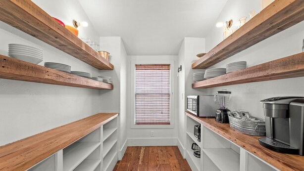 A narrow hallway with wooden shelves on either side, a window with blinds, and a coffee machine on the right. - Luxury 3 Bedroom House with Airstream, Cabin, Private Fireplace, and Plunge Pool (Comfort)