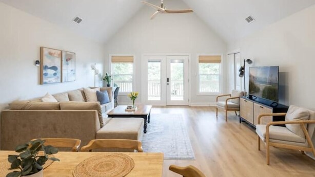 A spacious living room with a high ceiling fan, a large TV, and a cozy seating area with a sofa and chairs. - Newly Renovated, 1 min walk to beach, 3rd Row Emerald Isle Beach House (Emerald Isle)