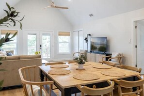 Ein Essbereich mit einem Holztisch, Stühlen und einem Fernseher im Hintergrund.