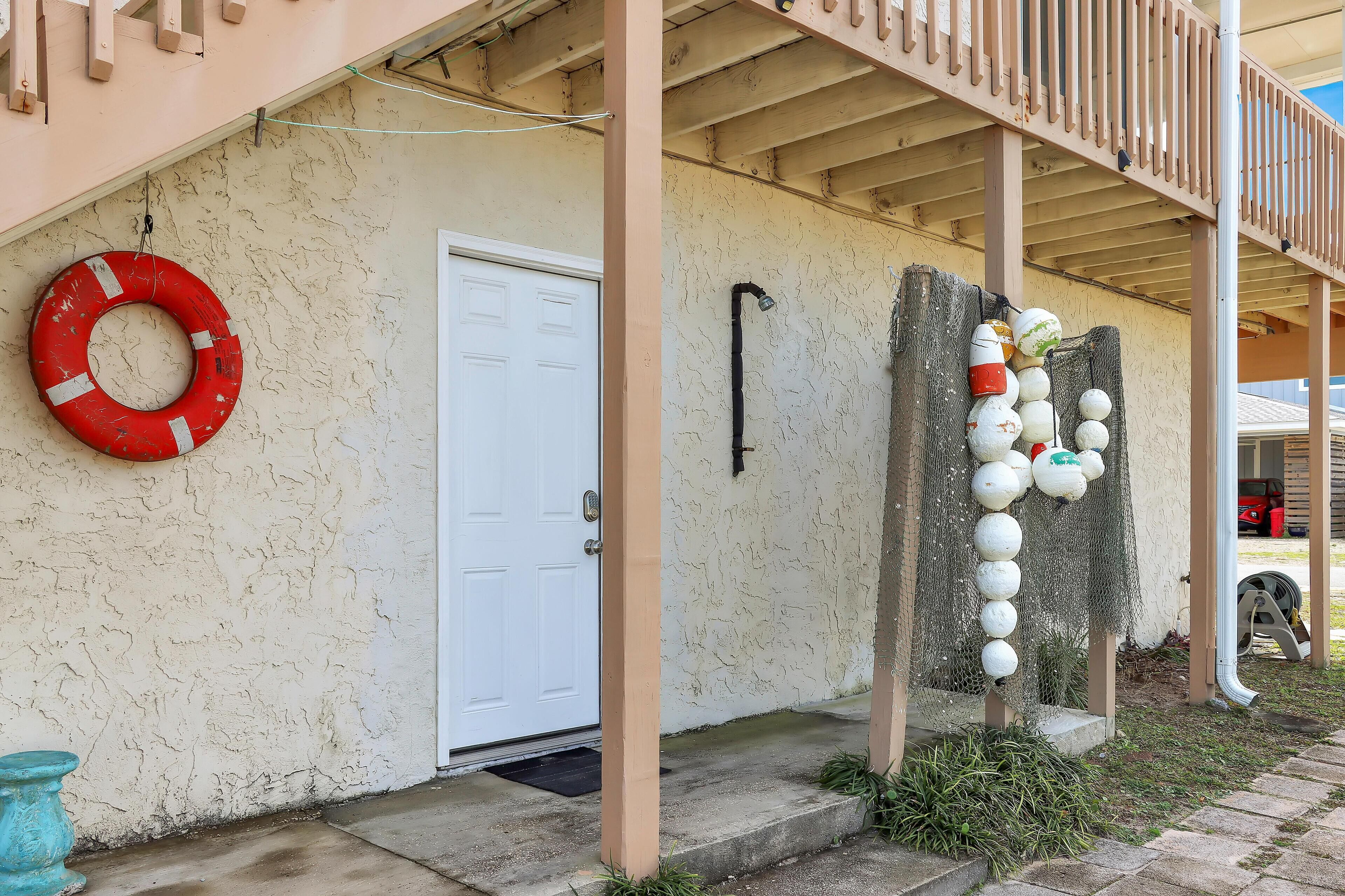 A building with a white door, a red lifebuoy, and a series of white and green decorative items on the exterior wall.