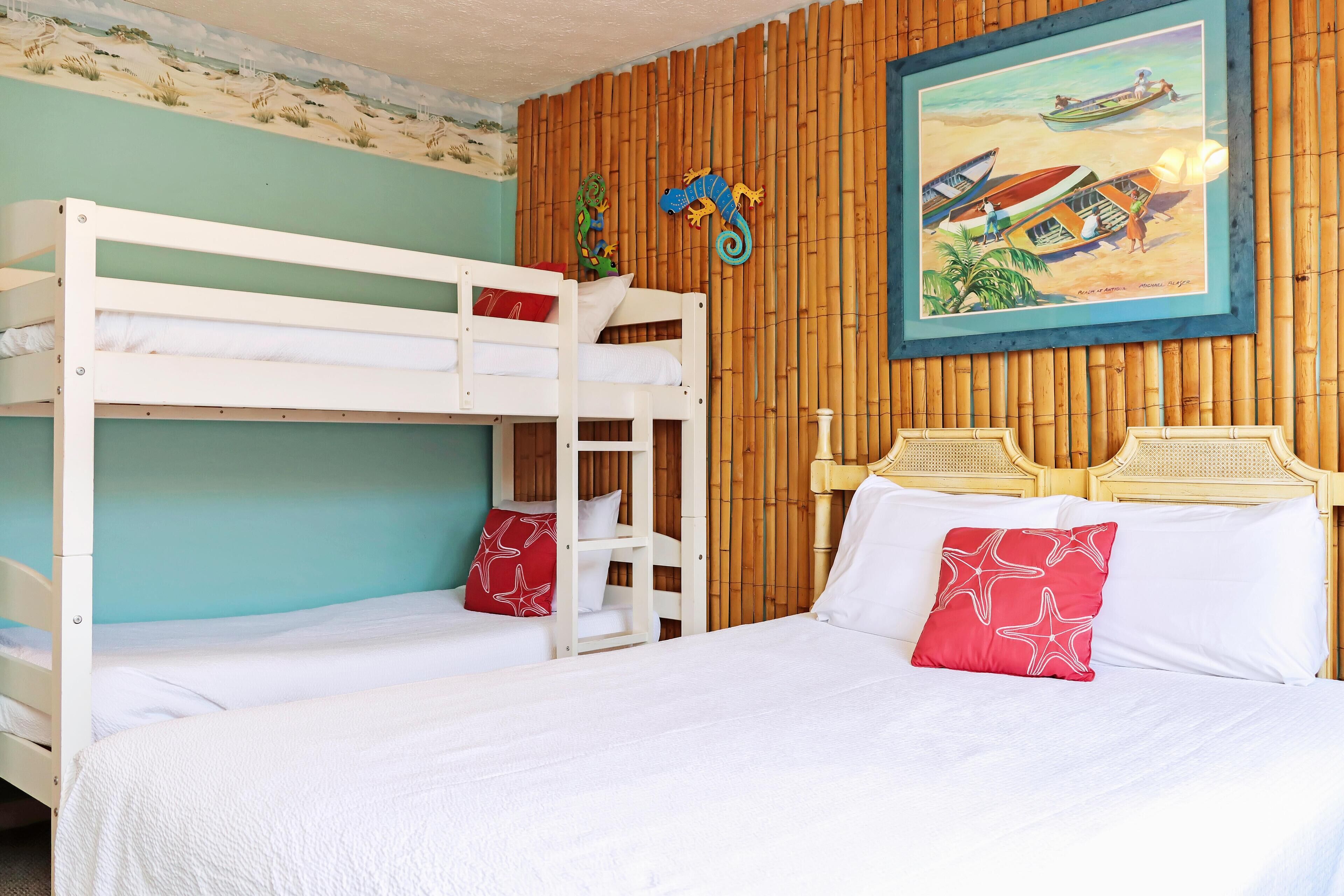 A room with bunk beds, a wooden headboard, and a beach-themed wall mural.