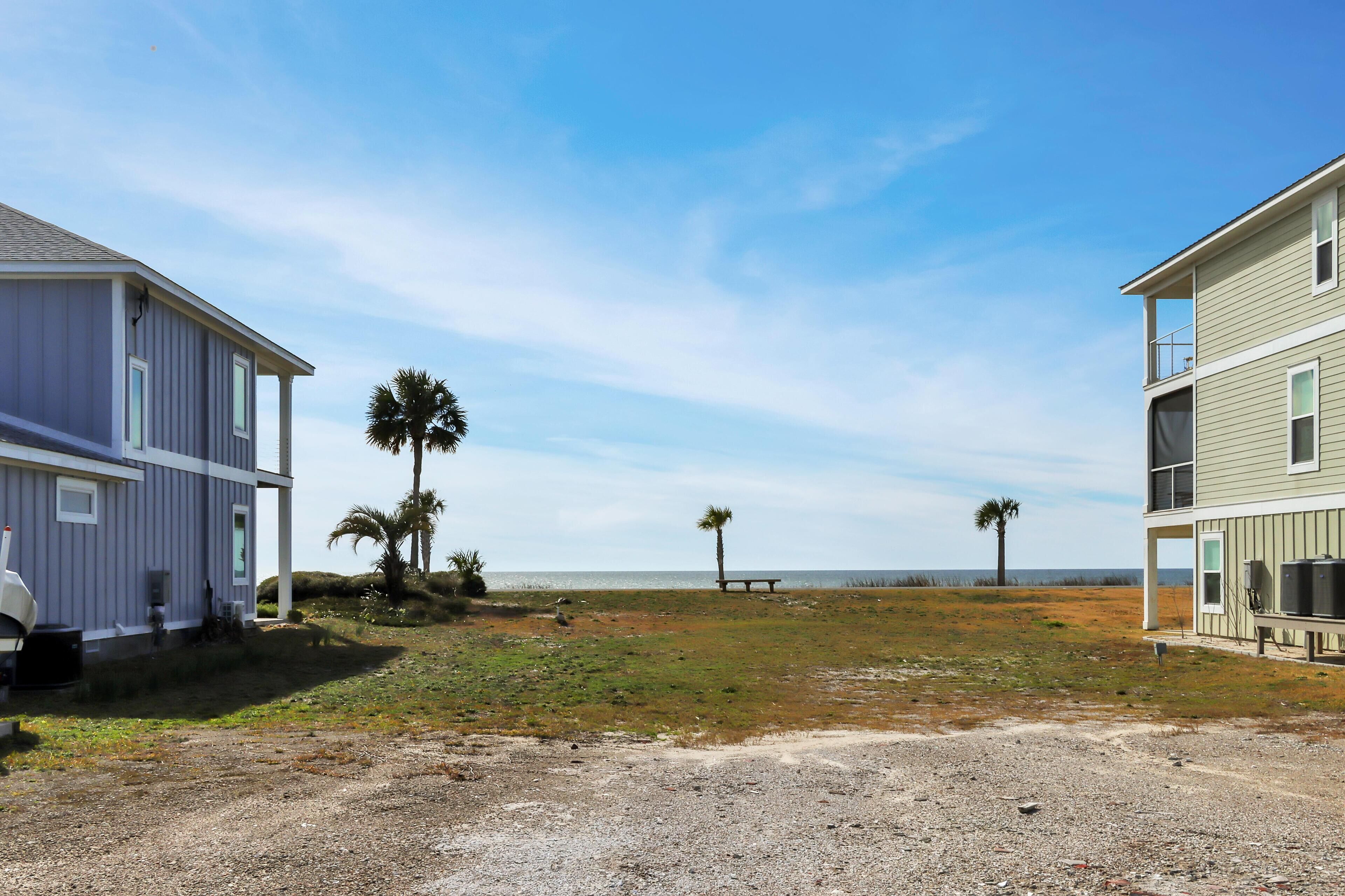 A coastal property with two houses, one with a porch and a grill, and the other with a balcony overlooking the beach.