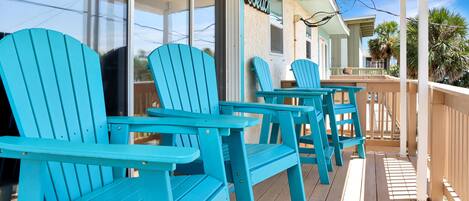 A porch with turquoise Adirondack chairs and a sign that reads "Beach".