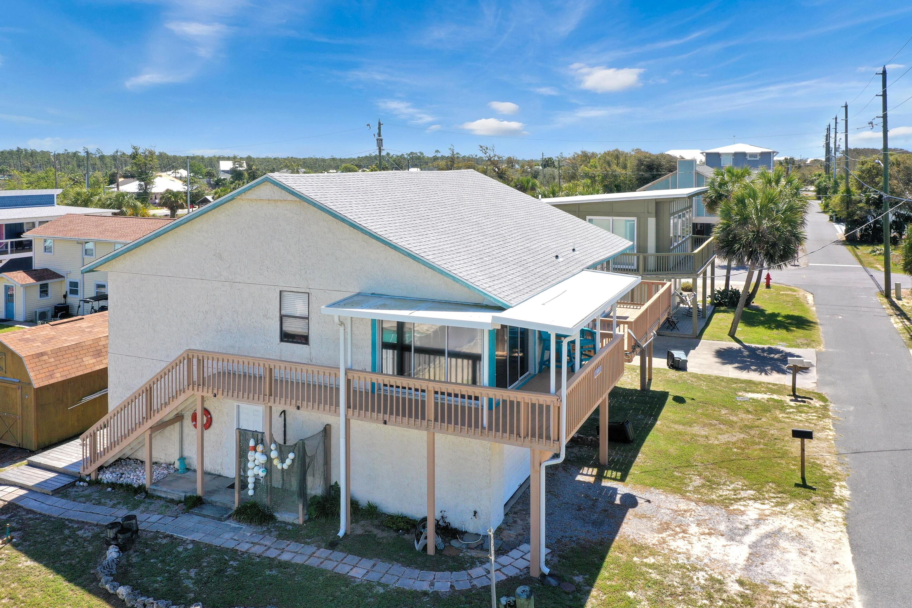 A single-story building with a balcony, a covered porch, and a small front yard.