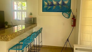 A kitchen with a bar area, a ceiling fan, a painting, and a fire extinguisher.