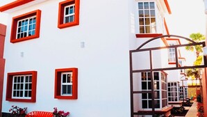 Ein weißes Gebäude mit roten Fensterrahmen und einem überdachten Gang.