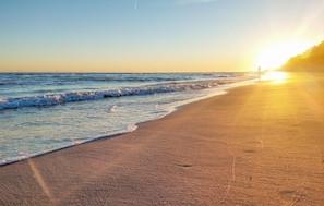 A beach with waves gently lapping at the shore and a sunset in the background. - 1 bedroom lovely home in Rewal (Rewal)