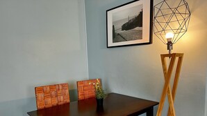 A dining table with two chairs, a framed picture on the wall, and a floor lamp.