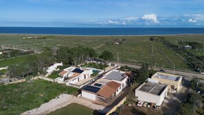 Ein Küstenwohngebiet mit Häusern, die mit Solaranlagen ausgestattet sind, mit freiem Blick auf das Meer und einer Straße, die parallel zum Strand verläuft.