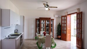 A compact kitchen with a dining area, a ceiling fan, and a large window.