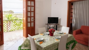 A dining area with a table set for four, a television, and a view of the outdoors.