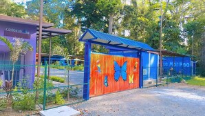 Een omheind gebied met een kleurrijke muurschildering van vlinders, een gebouw met een blauw dak en een bord met de tekst 'Caribbean Blue'.