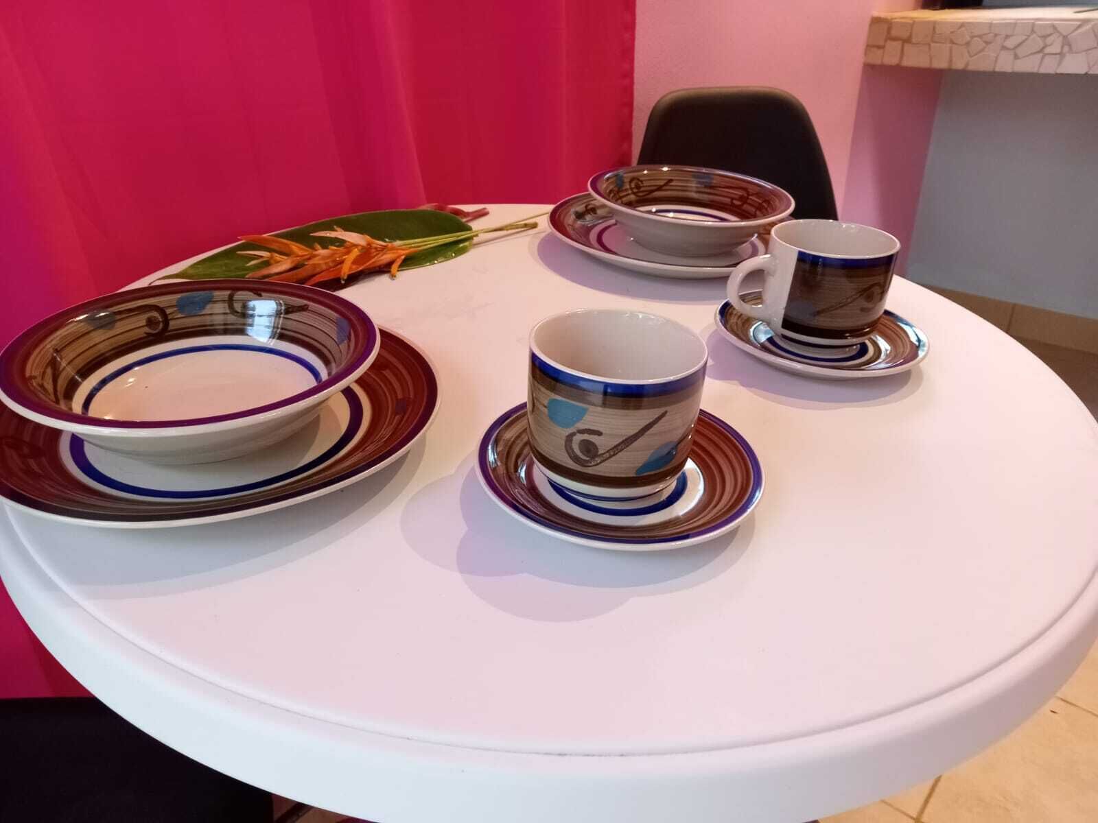 A round table with four bowls and two cups, each with a saucer.