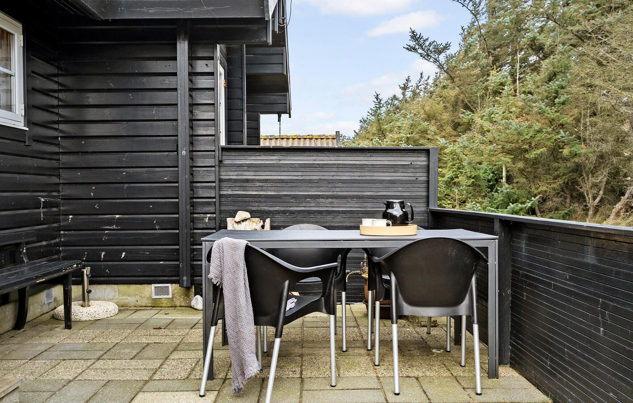 A black wooden building with a patio area featuring a table and chairs.