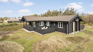 Une maison en bois à deux étages, dotée d’un porche couvert et d’une antenne parabolique.