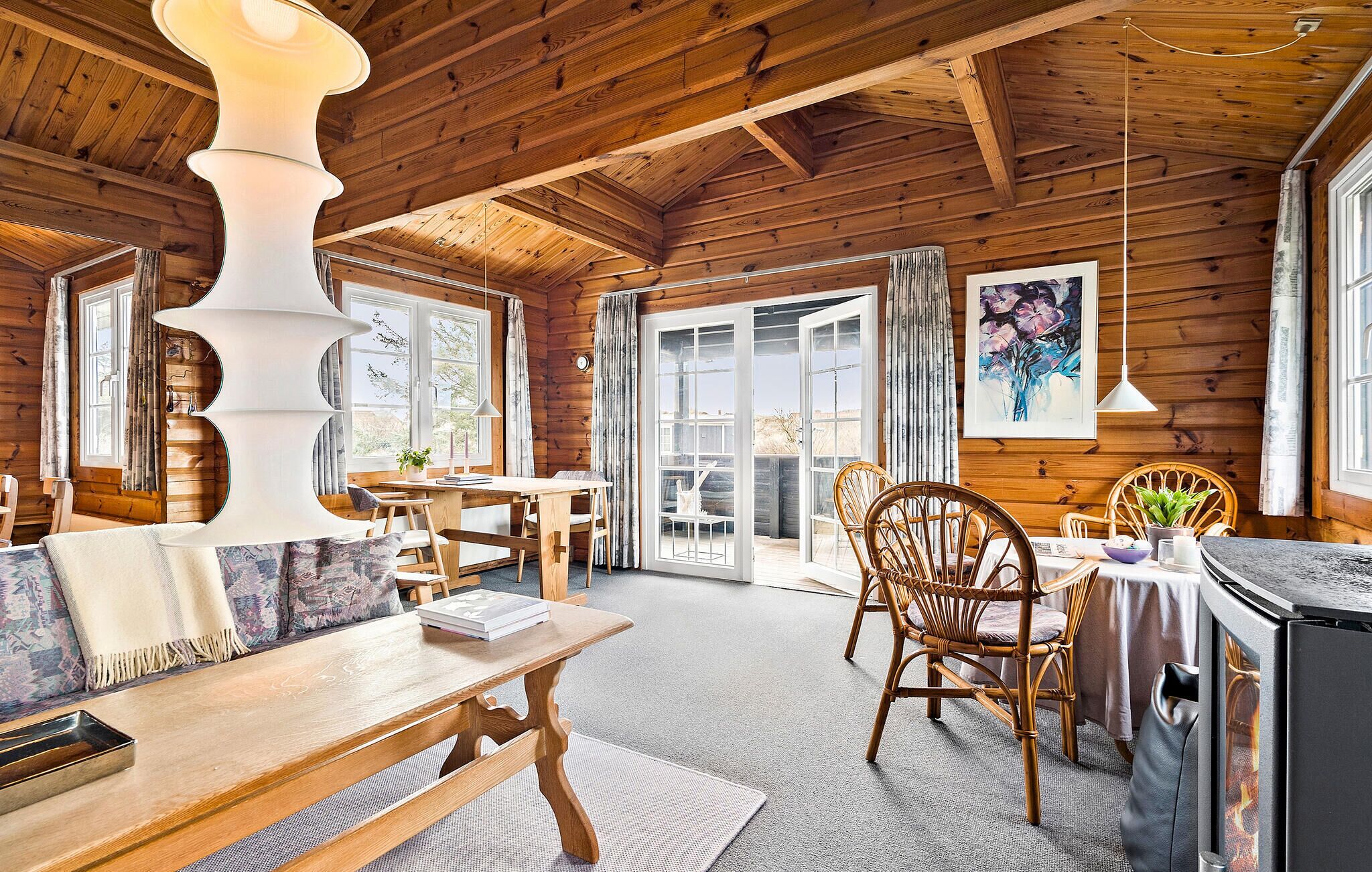 Accogliente interno di una baita in legno, con zona pranzo, mobili in legno e un'ampia finestra che offre vista sull'esterno.
