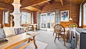 L’intérieur chaleureux d’un chalet en bois comprend un coin repas, des meubles en bois et une grande fenêtre donnant sur le paysage extérieur.