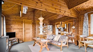 L’intérieur d’un chalet en bois chaleureux et accueillant, avec un canapé, une table basse, un téléviseur et un coin repas.