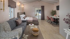 Ein modernes Schlafzimmer mit Bett, einer Couch, einem kleinen runden Tisch und einer Essecke mit Tisch und Stühlen.