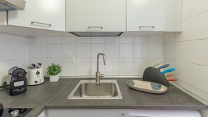 A modern kitchen with a stainless steel sink, white cabinets, a toaster, a coffee maker, and a knife block.