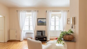 A living room with a sofa, TV, and a plant on a shelf.