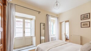 A bedroom with a bed, a window, a radiator, and a mirror.