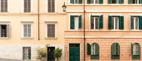 A row of buildings with multiple windows, some with shutters, and a cobblestone street.