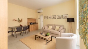 A living room with a sofa, coffee table, and dining area with chairs. - iFlat | Lovely in Trevi Fons Trevi II (Roma)