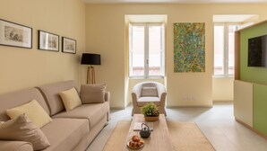 A living room with a sofa, armchair, coffee table, and artwork on the walls. - iFlat | Lovely in Trevi Fons Trevi II (Roma)