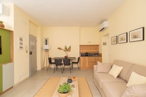A modern apartment with a dining area, kitchenette, and a living room with a sofa.