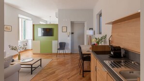 Una cucina moderna con forno a incasso, zona pranzo con tavolo e sedie e angolo salotto con divano e tavolino.