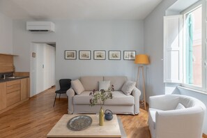 A modern living room with a sofa, a coffee table, and a vase with flowers.